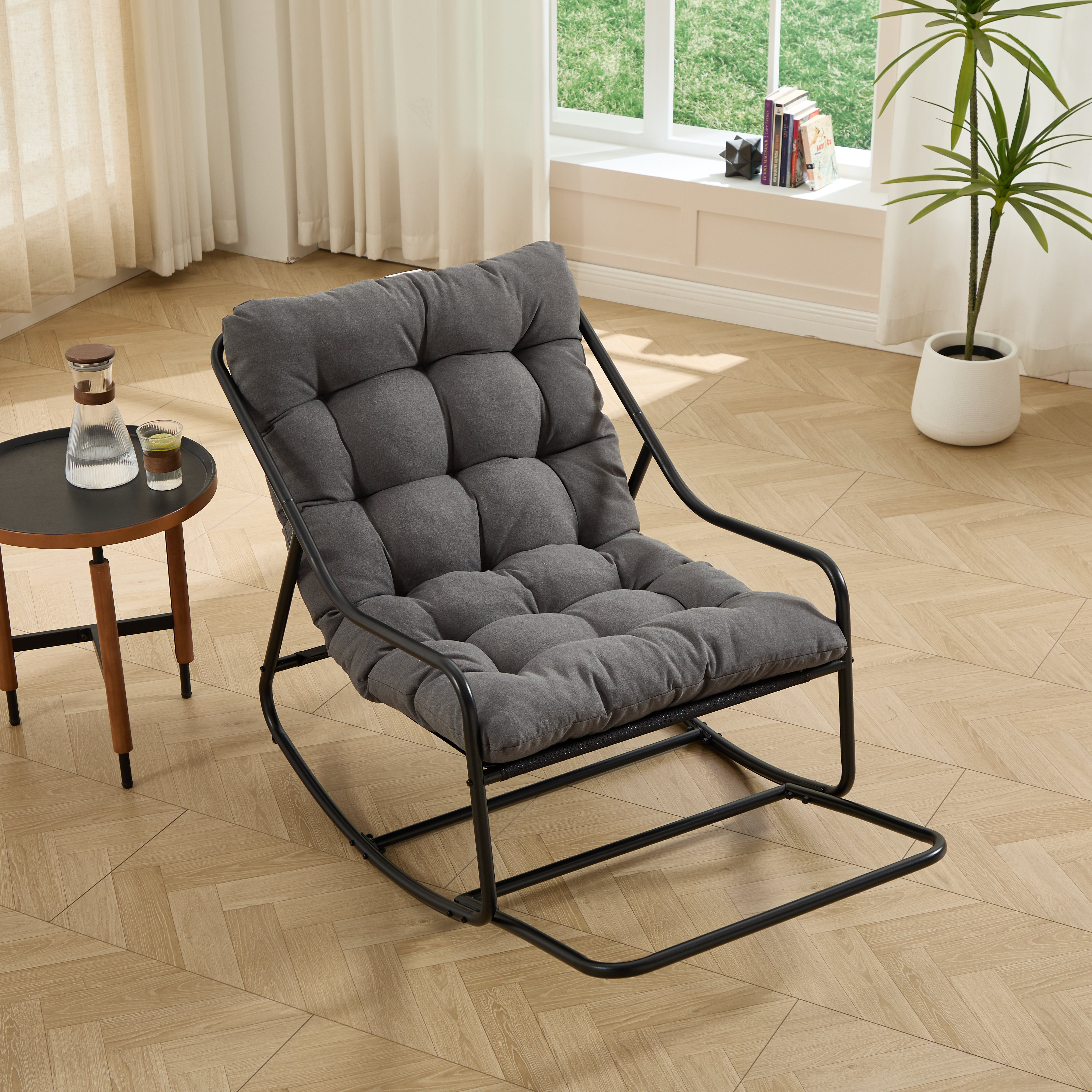 Silla mecedora para exterior con cojín cómodo y grueso, estructura negra y gris.
